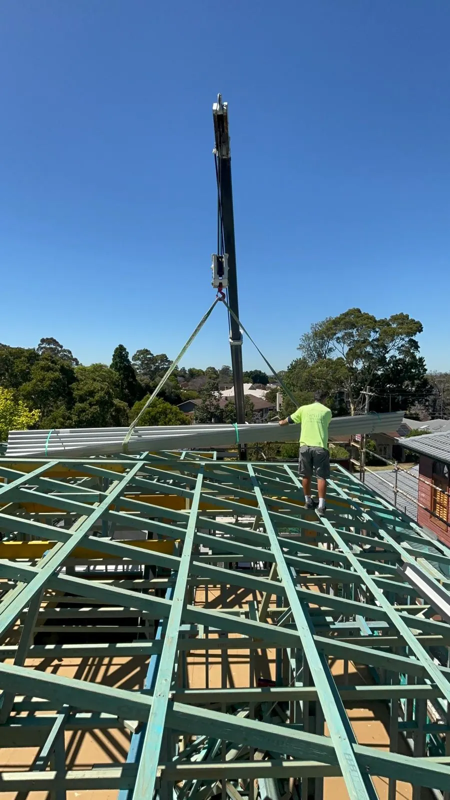 Roofers lifting metal roof sheets into place